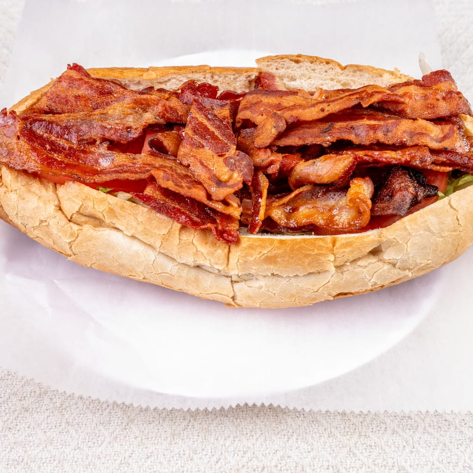 Pete's-A-Place's bacon sub sandwich, overflowing with crispy bacon strips on a white plate.
