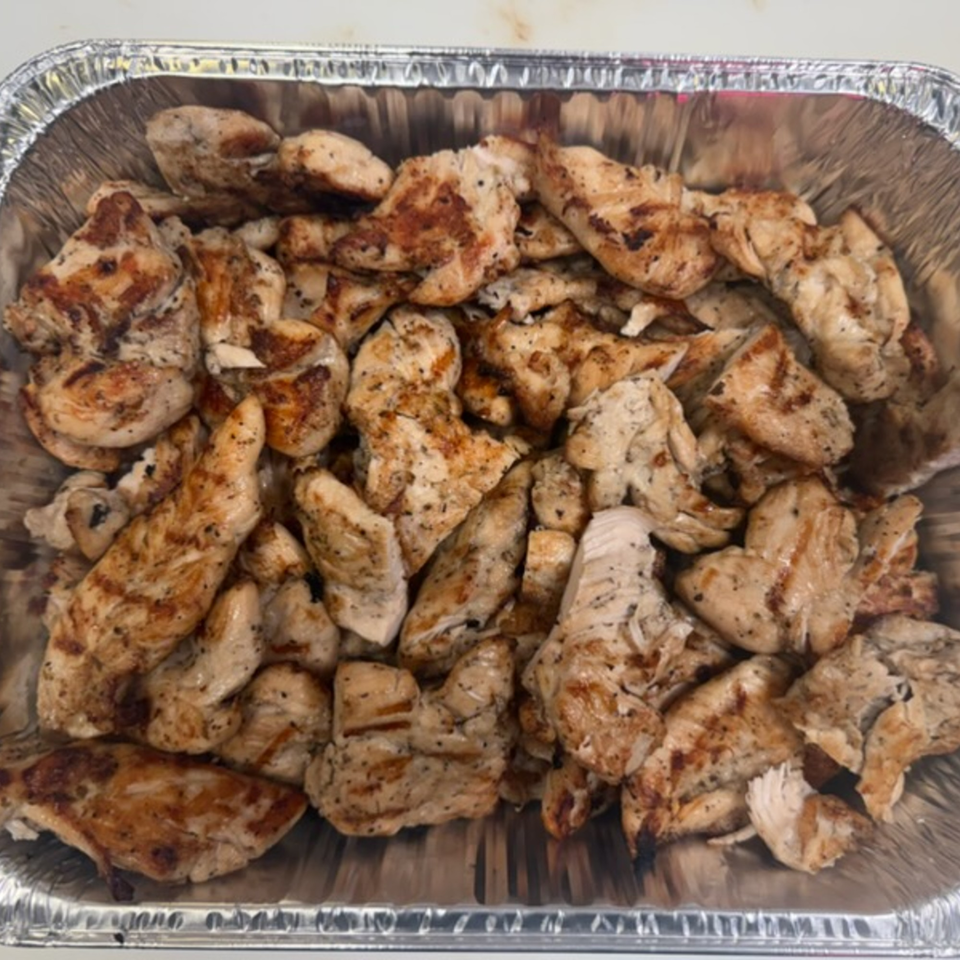 Grilled chicken pieces, seasoned and browned, in a foil catering pan from Pete's-A-Place.