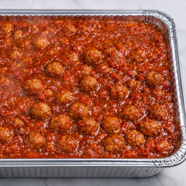 A large catering tray filled with Pete's-A-Place meatballs simmering in rich red marinara sauce.