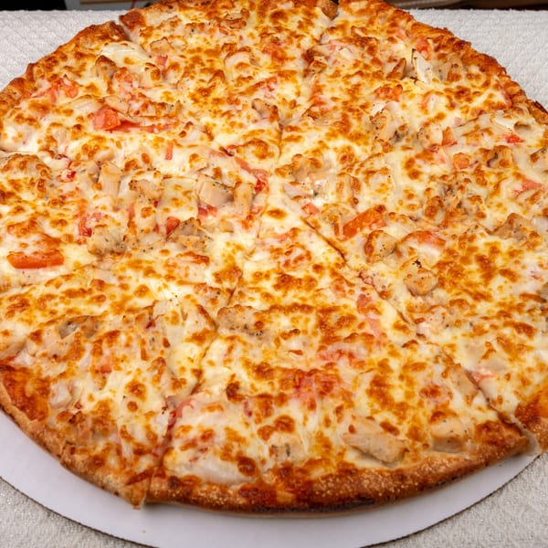 A whole Pete's-A-Place pizza with melted cheese, chicken, and diced tomatoes.