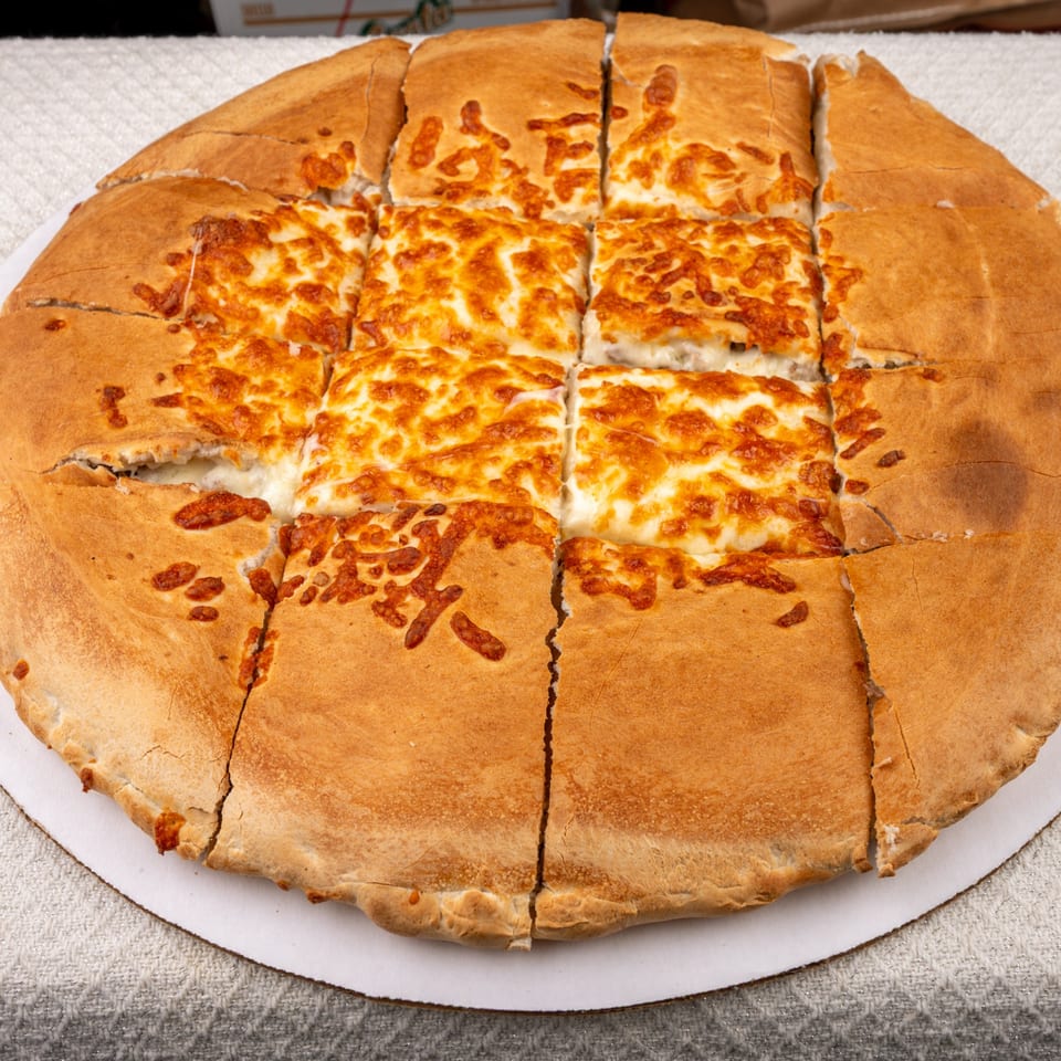 A large, round Pete's-A-Place cheese pizza, cut into squares, with a thick golden crust.