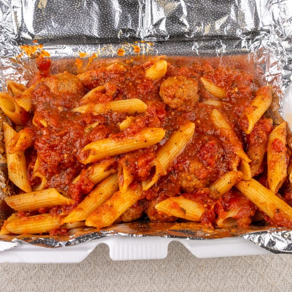 Penne pasta with meatballs and marinara sauce in a foil-lined to-go container from Pete's-A-Place.